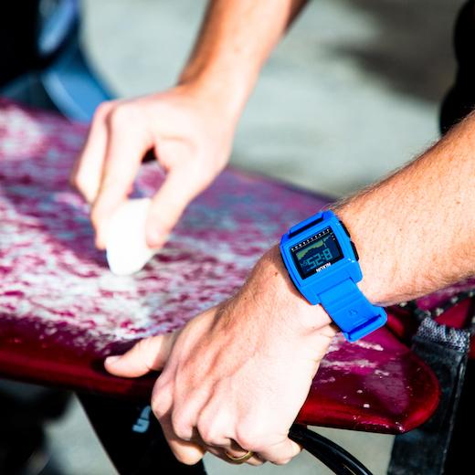Waxing up a surfboard, flexing the Nixon watch.