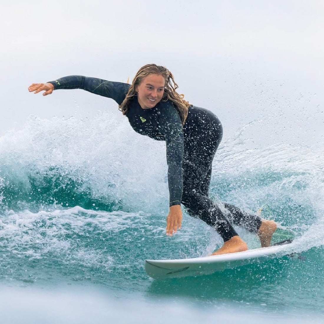 A woman surfer wearing a Roxy wetsuit as she surfs a medium wave - Melbourne Surfboard Shop