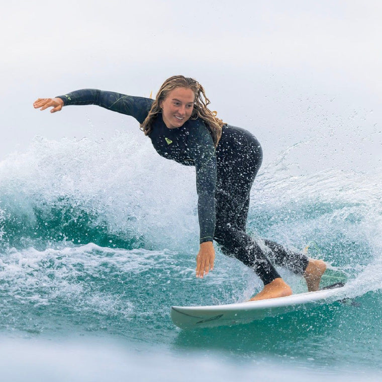A woman surfer wearing a Roxy wetsuit as she surfs a medium wave - Melbourne Surfboard Shop