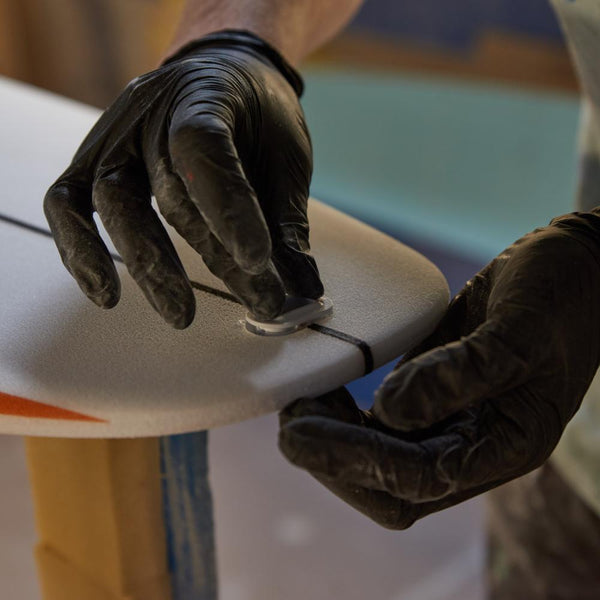 Installing a fin plug on the surfboard tail.