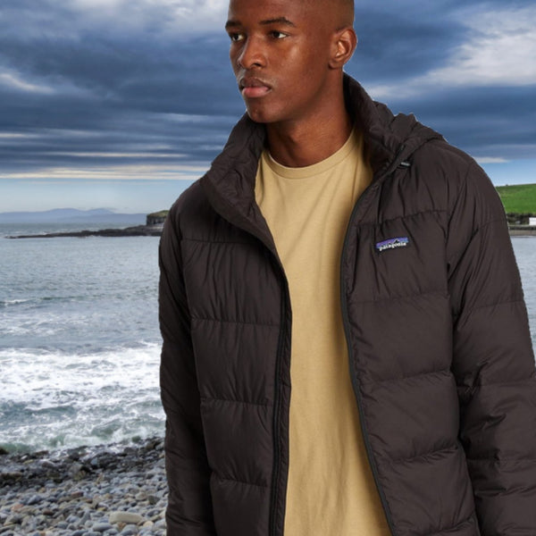 Bloke in a Patagonia jacket, strolling along a pebble beach.