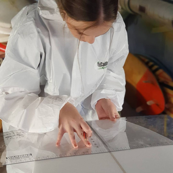 Preparing a surfboard blank with measuring tools.