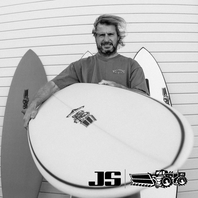 Man holding a Bull Run surfboard with 'JS' logo against a wooden background at Melbourne Surfboard Shop