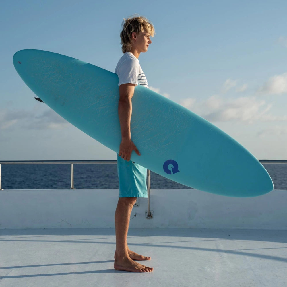 Man holding a Torq Surfboard while ona boat deck.